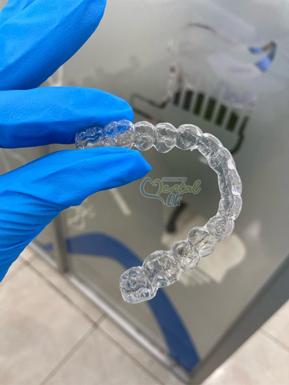 Retenedor de acetato transparente sostenido con guantes, listo para entregar al paciente
